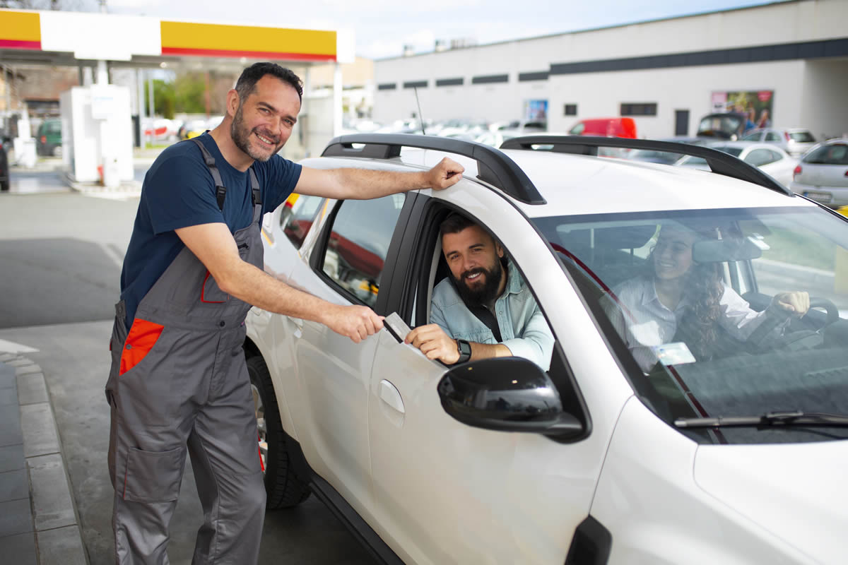 Un treballador del taller de pintura fa entrega del vehicle a dos clients asseguts al seu interior, com a part d’un servei pensat per oferir màxima comoditat.
